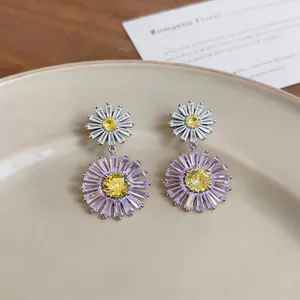 Detailed view of daisy zircon drop earrings with purple and yellow crystals