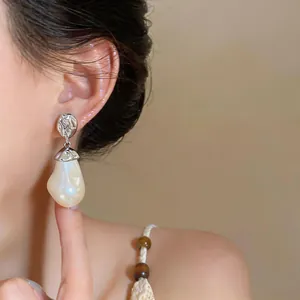 Detail of baroque pearl drop earring with textured silver metal stud on model