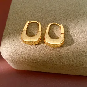 Primo piano di orecchini a cerchio a U placcati in oro 18K con dettagli a trama increspata.