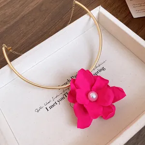 Detail shot of a vintage gold choker featuring a vibrant fuchsia flower with a pearl center.