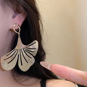 Detailed view of golden metallic leaf earrings with elegant pleated textured finish