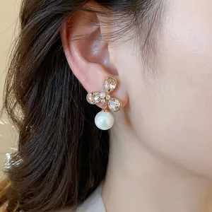 Elegantes pendientes de flor de circón bañados en oro de 18k con perla en modelo.