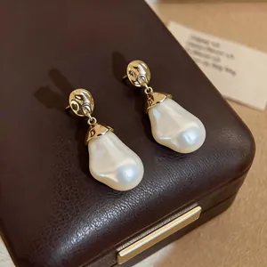 Close-up detail of golden wrinkled texture and baroque pearl on silver needle stud earrings