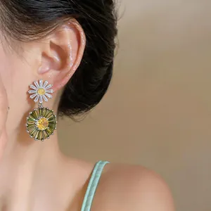 Detail view of zircon floral drop earrings with yellow and green daisy design