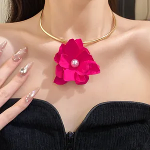 Close-up of a vintage magenta fabric flower choker with pearl center on a gold collar.