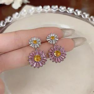 Close-up of elegant floral drop earrings featuring pink and white petals with yellow centers