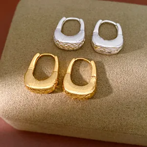 Vista macro di orecchini a cerchio a forma di U strutturati placcati in oro 18 carati