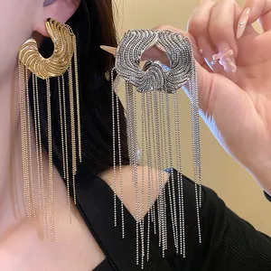 Close-up of elegant gold and silver C-shaped earrings featuring long beaded chain tassels