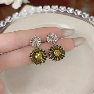 Detailed close-up showing fresh green and white zircon floral drop earrings held by hand.