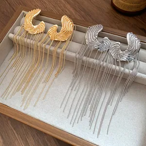 Detailed view of gold and silver C-shaped tassel earrings with bead chains.