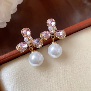 Primer plano detallado de pendientes de flor y perla chapados en oro 18k con circonita