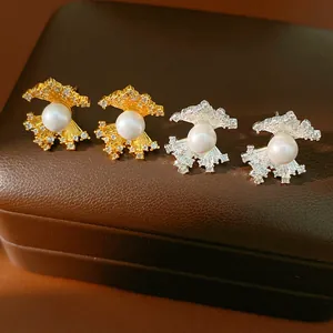 Detailed macro view of fan-shaped zircon pearl earrings in elegant gold and silver tones