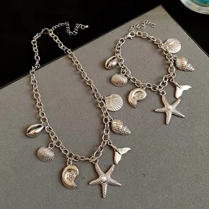 Close-up detail of silver-tone necklace and bracelet set featuring ocean seashell charms