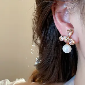 Primer plano de pendientes de flor de circón bañados en oro 18k con perla colgante