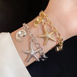 Detailed view of gold and silver starfish charm bracelets featuring pearls and seashells on wrist