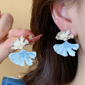 Detailed close-up of blue enamel ginkgo leaf earrings with silver needle finish.