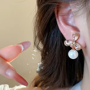 Primer plano de pendientes de flores bañados en oro de 18k con circonitas y perla