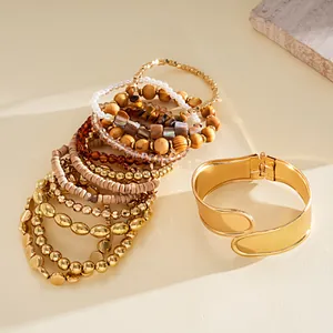 Détail de 12 bracelets avec manchette dorée et perles variées sur une surface beige.
