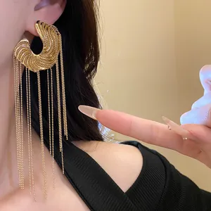 Detailed view of fashionable C-shaped gold tassel earrings with long bead chains