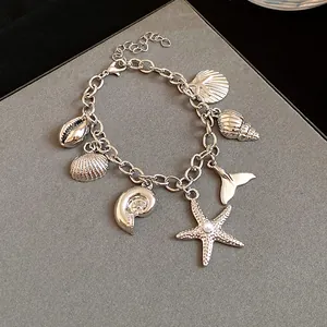 Close-up detail of a silver ocean-themed charm bracelet featuring starfish and shells