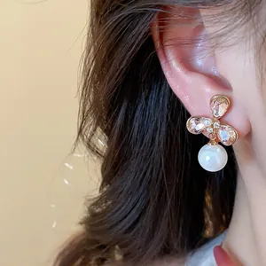 Detalle de un pendiente de flor chapado en oro de 18k con una perla blanca colgante