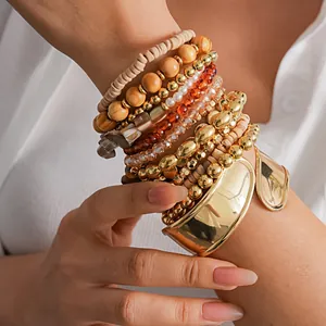 Gros plan d'un ensemble de 12 bracelets bohèmes avec manchette dorée et perles en bois empilées