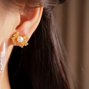 Detailed view of elegant fan-shaped gold earrings with pearl and zircon inlay