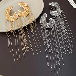Close-up of elegant gold and silver C-shaped earrings featuring long beaded tassels.