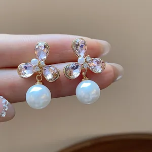 Detalle de pendientes de flores bañados en oro de 18 quilates con cristal rosa y perla