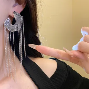 Elegant silver C-shaped hoop earrings with long metallic fringe tassels worn by model