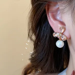Primer plano detallado de pendientes de flor de circón y perla bañados en oro 18k