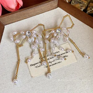 Elegant gold bow earrings featuring white pearls and clear zircons on a vintage display card
