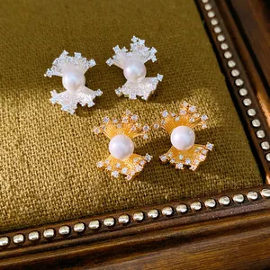 Detailed macro view of fan-shaped pearl stud earrings with zircon accents on green fabric