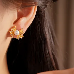 Detail shot of elegant gold-tone fan-shaped earrings with a central pearl and zircons