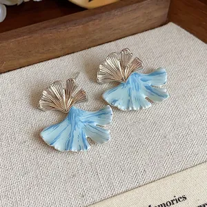 Detailed macro view of elegant ginkgo leaf stud earrings with blue marbled enamel finish