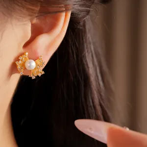 Macro view of fan-shaped gold earring featuring a central pearl and zircon stone accents