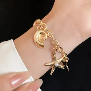 Close-up detail of a gold nautical charm bracelet with starfish and shell pendants