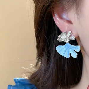 Detailed close-up of elegant ginkgo leaf stud earrings with a blue drip oil finish