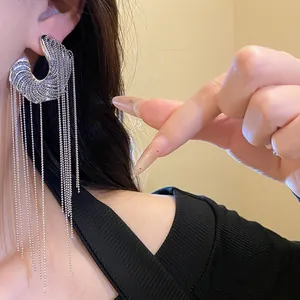 Detail view of silver needle C-shaped earrings with long delicate bead chain tassels.