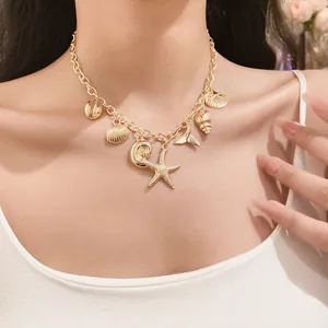 Detailed view of a gold ocean-themed necklace with starfish and shell charms on model