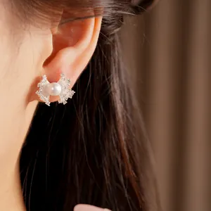 Detail view of elegant fan-shaped pearl stud earrings with zircon on a model ear