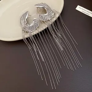 Detail showing elegant silver C-shaped stud earrings with long cascading bead tassels