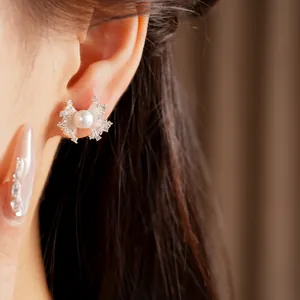 Close-up detail of a silver zircon fan-shaped pearl stud earring worn on the ear