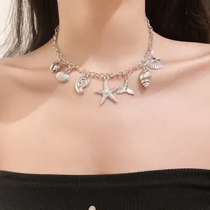 Close-up of a silver sea-themed necklace with starfish and shell charms on model.