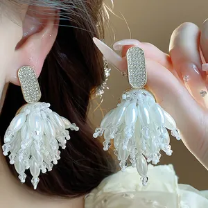 Close-up detail of luxury silver needle earrings with rhinestone and pearl tassels