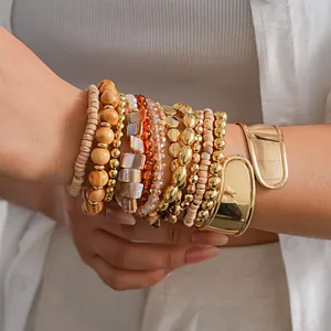 Détail d'un ensemble de 12 bracelets bohèmes avec joncs dorés, perles de bois et cristaux.