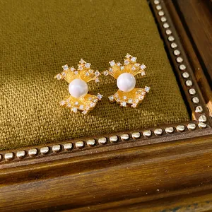 Detailed close-up of fan-shaped gold stud earrings with elegant pearls and zircons