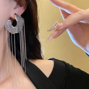 Detailed close-up view of silver C-shape earrings with long bead tassel chains on a model