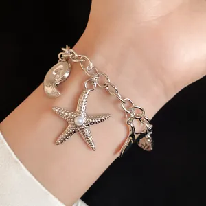 Detailed view of a silver sea-themed charm bracelet with starfish and pearl charms