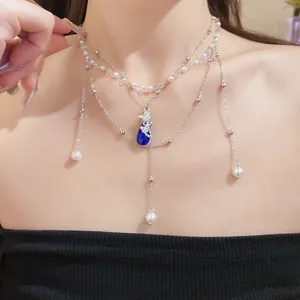 Detail view of a multilayer pearl necklace featuring a blue butterfly teardrop pendant